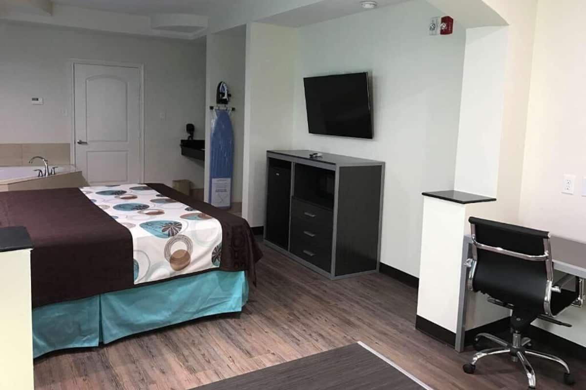 A hotel room with a bed, a desk, a chair, a TV, a wardrobe, and a bathroom.