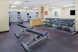 A gym with cardio machines, weight benches, and dumbbells. - TownePlace Suites by Marriott Cookeville (Cookeville)