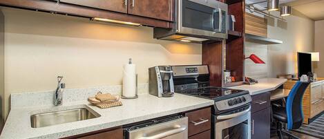 Una cocina moderna con electrodomésticos de acero inoxidable, lavavajillas y armarios de madera.
