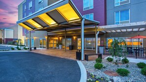 A hotel entrance with a covered walkway, outdoor seating, and a landscaped garden area. - TownePlace Suites by Marriott Cookeville (Cookeville)