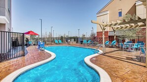 A swimming pool with a tiled deck, surrounded by lounge chairs and umbrellas. - TownePlace Suites by Marriott Cookeville (Cookeville)