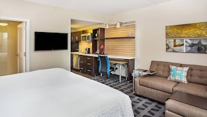 A hotel room with a large bed, a sofa, a desk with a chair, a flat-screen TV, a microwave, and a coffee maker. - TownePlace Suites by Marriott Cookeville (Cookeville)
