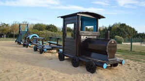 A wooden play structure with a train theme, including a cabin and a locomotive, on a sandy area with trees and a fence in the background. - Quiet holiday home by the sea in the Loire (Talmont-St. Hilaire)