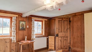 A wooden room with a bed, dresser, and two windows.