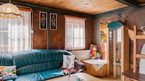 A cozy room with a teal leather sofa, a wooden cabinet with a glass door, and a ceiling fan.