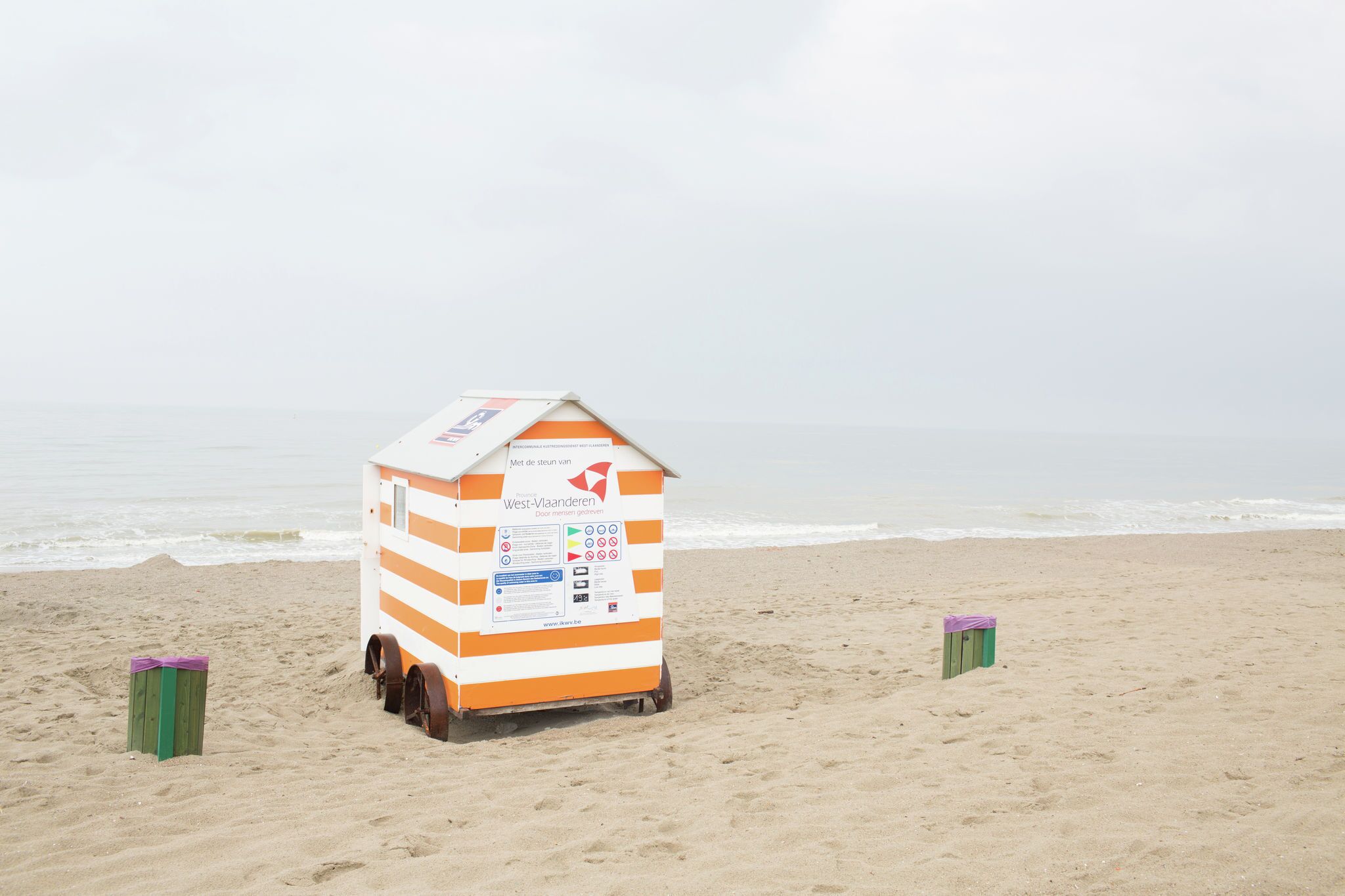 Una cabaña playera con diseño a rayas, una dirección web y un pequeño letrero.