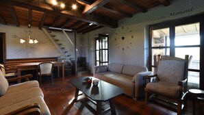 Un soggiorno accogliente con soffitto in legno, un divano, una poltrona, un tavolo e una scala.