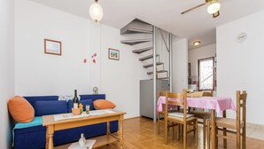 Un salon moderne avec un canapé bleu, une table basse en bois et un coin repas agrémenté d’une nappe rose.