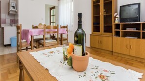 Un coin repas avec une table dressée pour deux personnes, une bouteille de vin et une plante en pot.