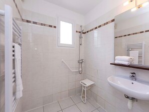 Une salle de bain moderne avec une douche à l’italienne, un lavabo blanc et un porte-serviettes.