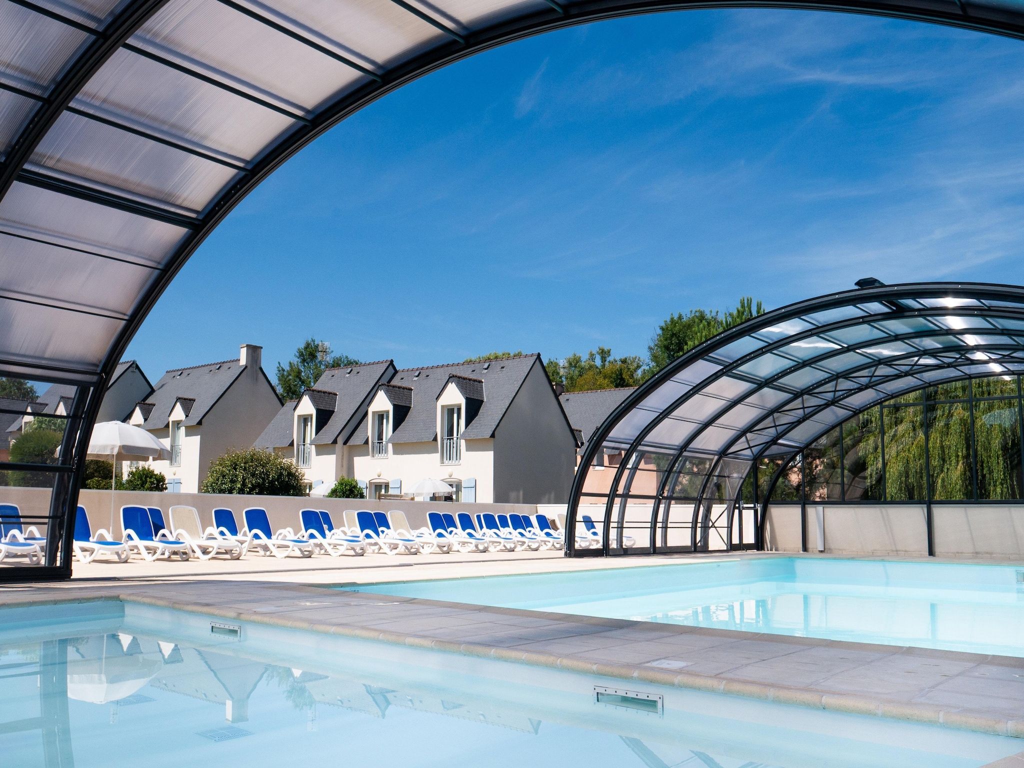 Une piscine avec des chaises longues et un espace abrité.