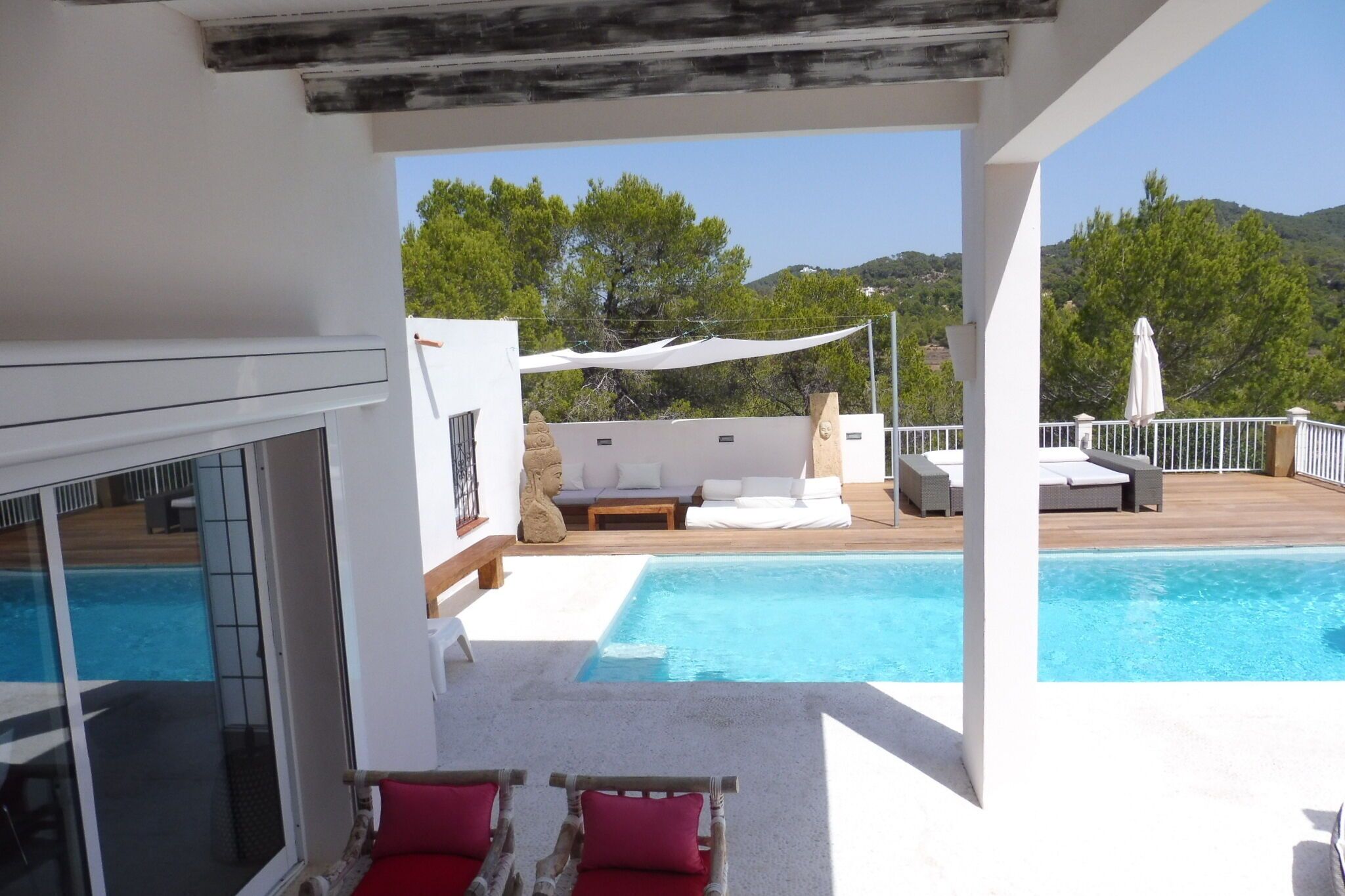 A poolside area with a view of the pool, a white umbrella, and a stone sculpture.