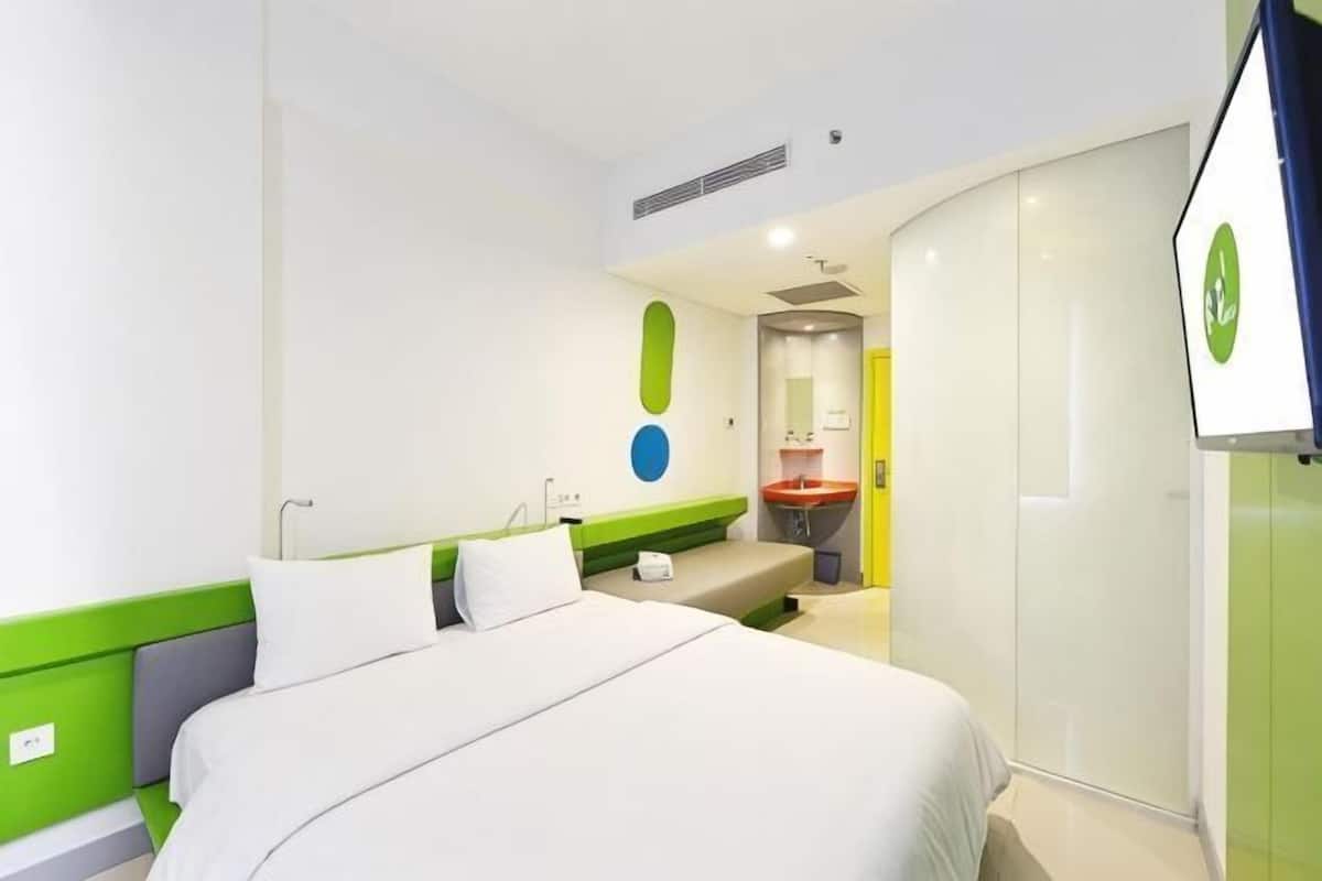 A hotel room with a bed, a sink, and a mirror.