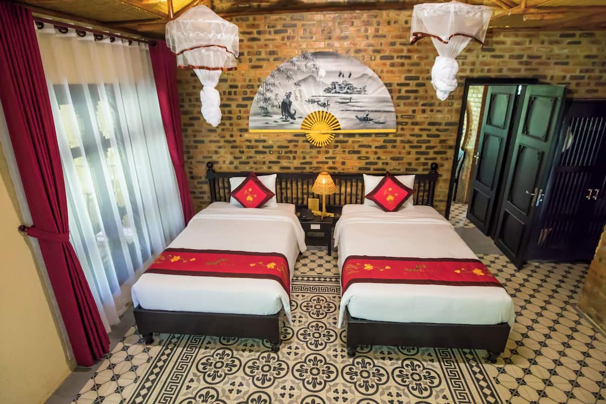 A hotel room with two beds, a traditional Chinese painting on the wall, and a patterned floor.