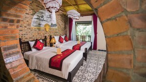 A traditional room with a brick wall, two beds with red and white bedding, a patterned floor, and hanging lanterns. - Hue Ecolodge (Hue)