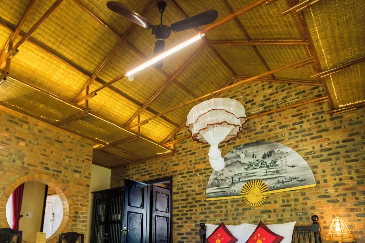 Una habitación con una cama, ventilador de techo, pared decorada con un mural y piso con diseño.