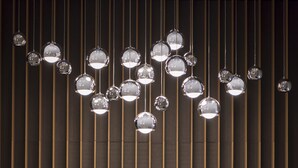 A reception area with a modern design, featuring a reception desk, a receptionist, and multiple hanging spherical light fixtures. - Courtyard by Marriott Brno (Brno)