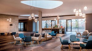 A spacious lounge area with modern furniture, large windows, and hanging spherical light fixtures. - Courtyard by Marriott Brno (Brno)