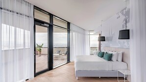 A modern bedroom with a large bed, a balcony with a view, and a sliding glass door. - Courtyard by Marriott Brno (Brno)