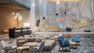 Un vestíbulo moderno con mostrador de recepción, zona de estar y un mural grande.