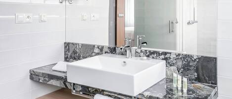 A modern bathroom with a white sink, marble countertop, and a mirror above.