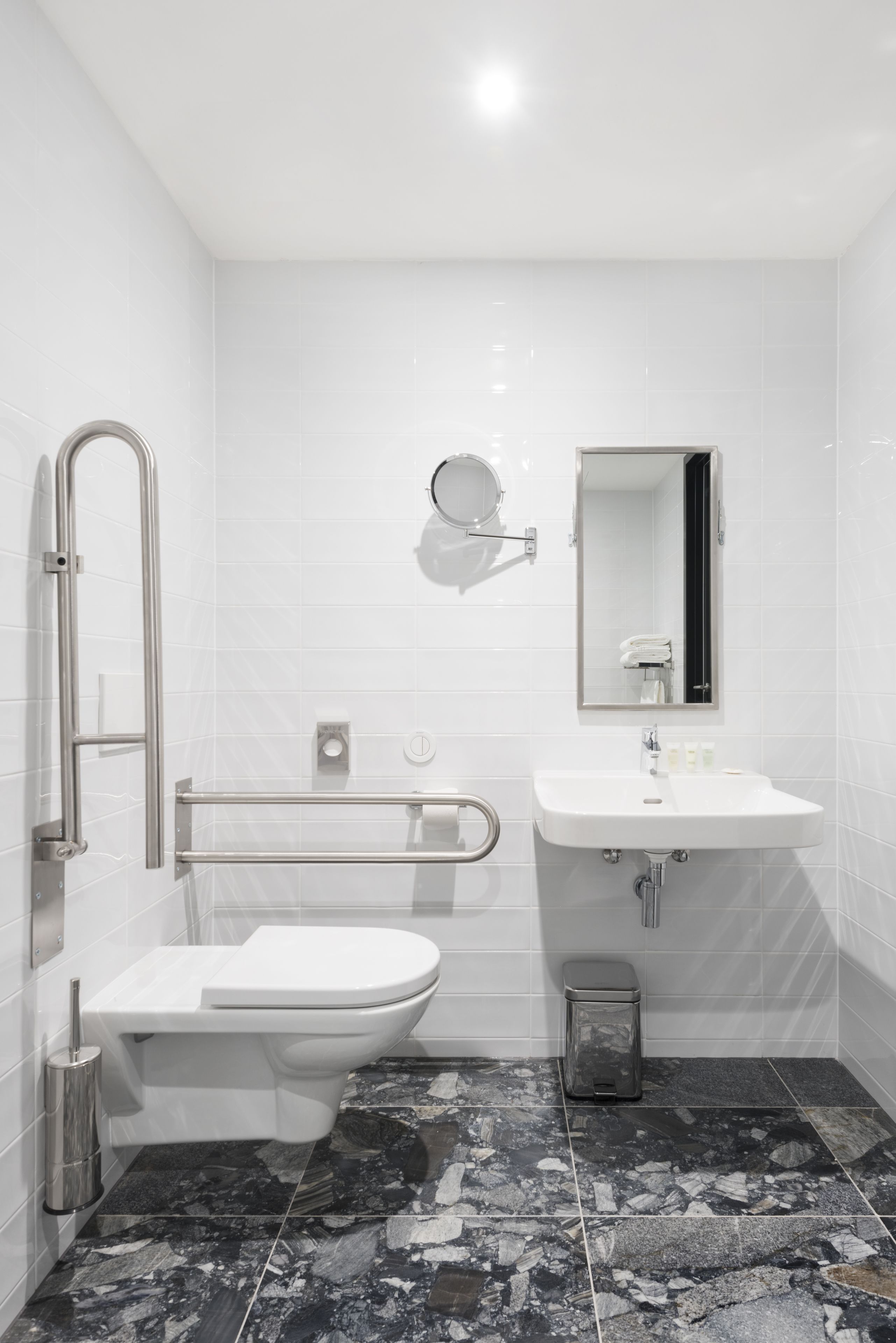A modern bathroom with a white toilet, a sink, and a mirror.