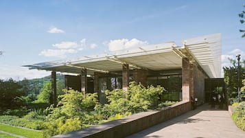 Un edificio moderno con una galería techada y vistas a un paisaje verde exuberante.