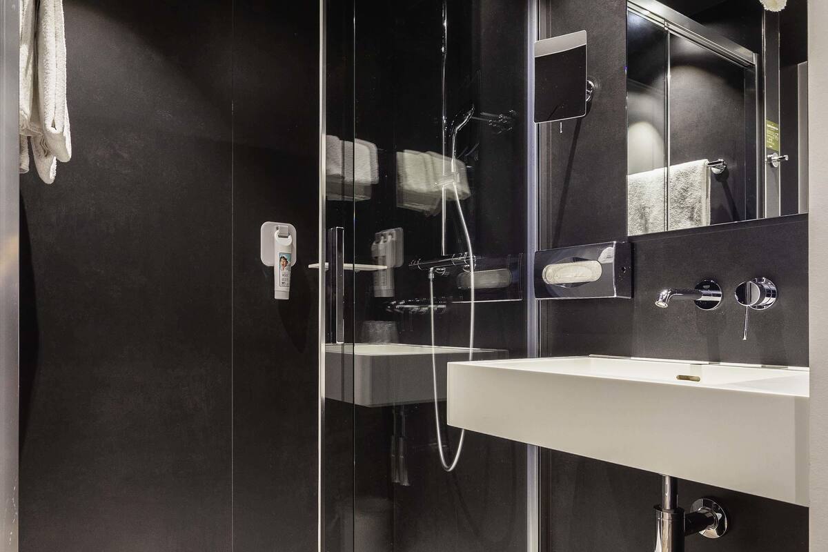 A modern bathroom with a glass shower enclosure, a white sink, and a mirror.