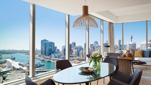 A modern dining area with a glass table, chairs, and a city view. - Sofitel Sydney Darling Harbour (Sydney)