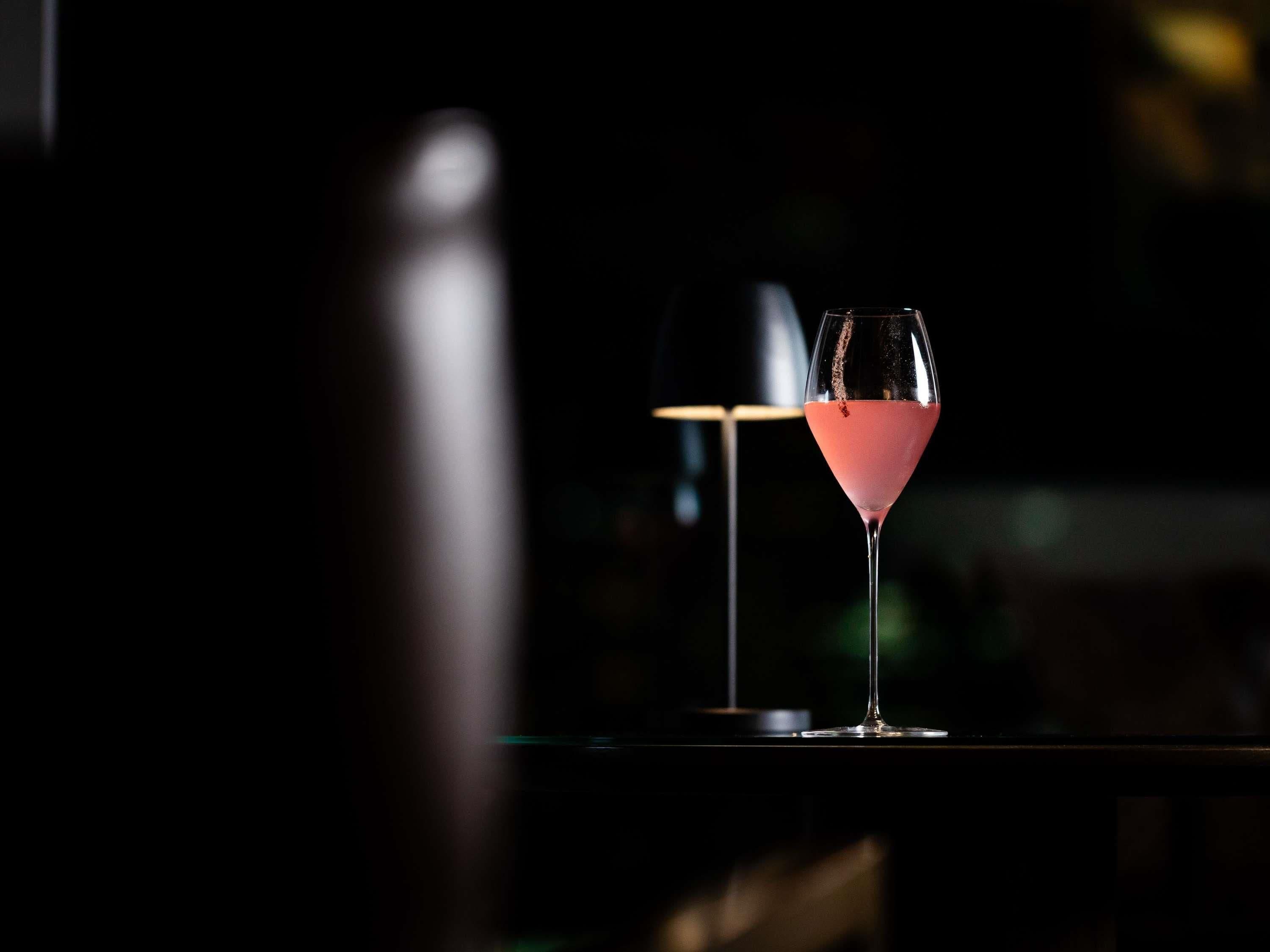 Två glas med en rosa dryck står på ett bord, med en lampa i bakgrunden.