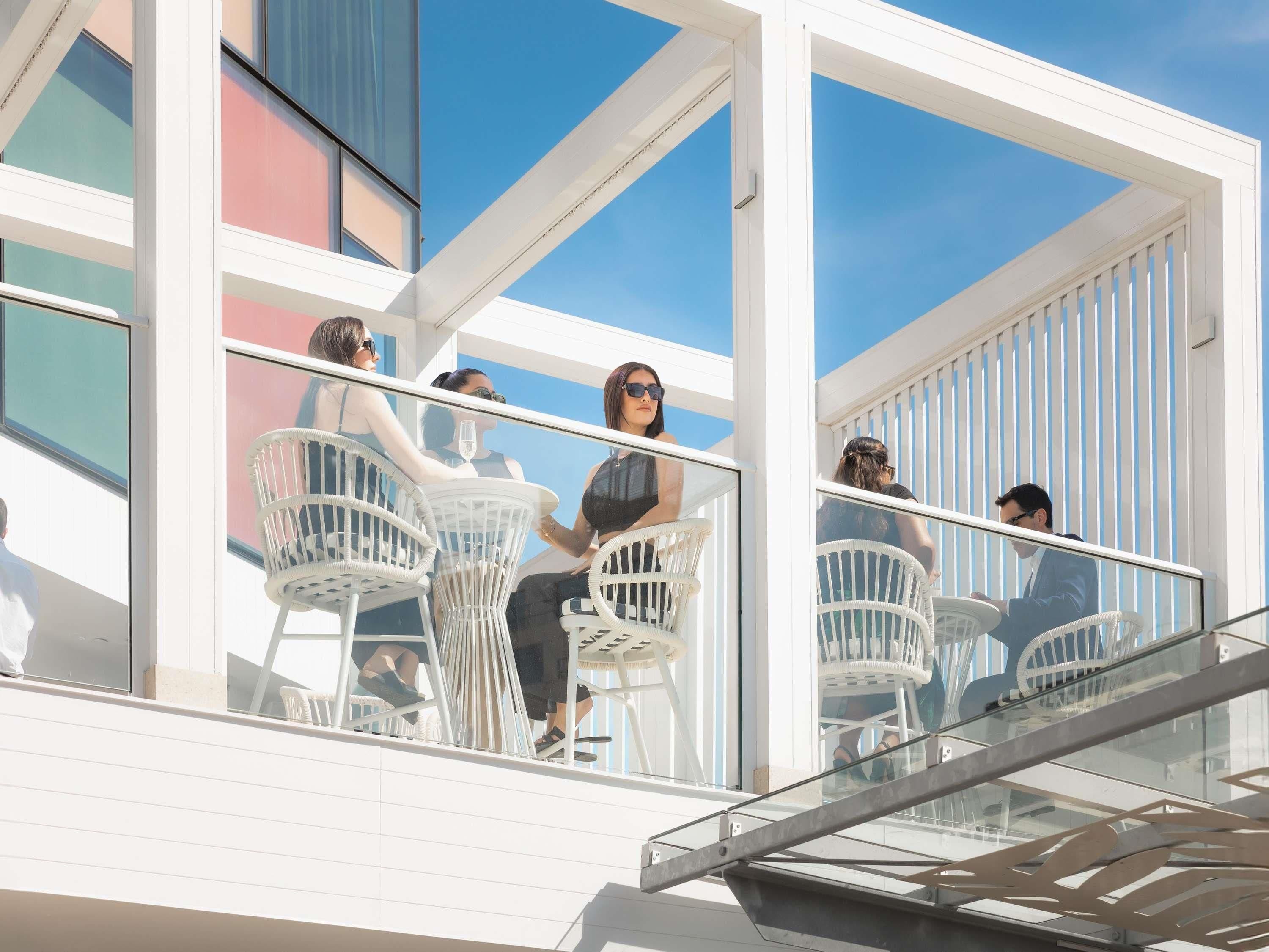 A modern building with large windows and white outdoor seating.