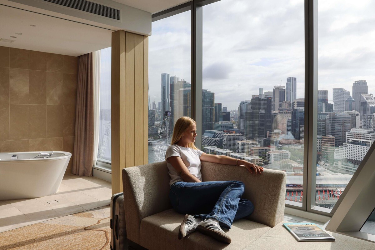 Habitación de hotel moderna con un ventanal grande, una bañera y vistas a la ciudad.