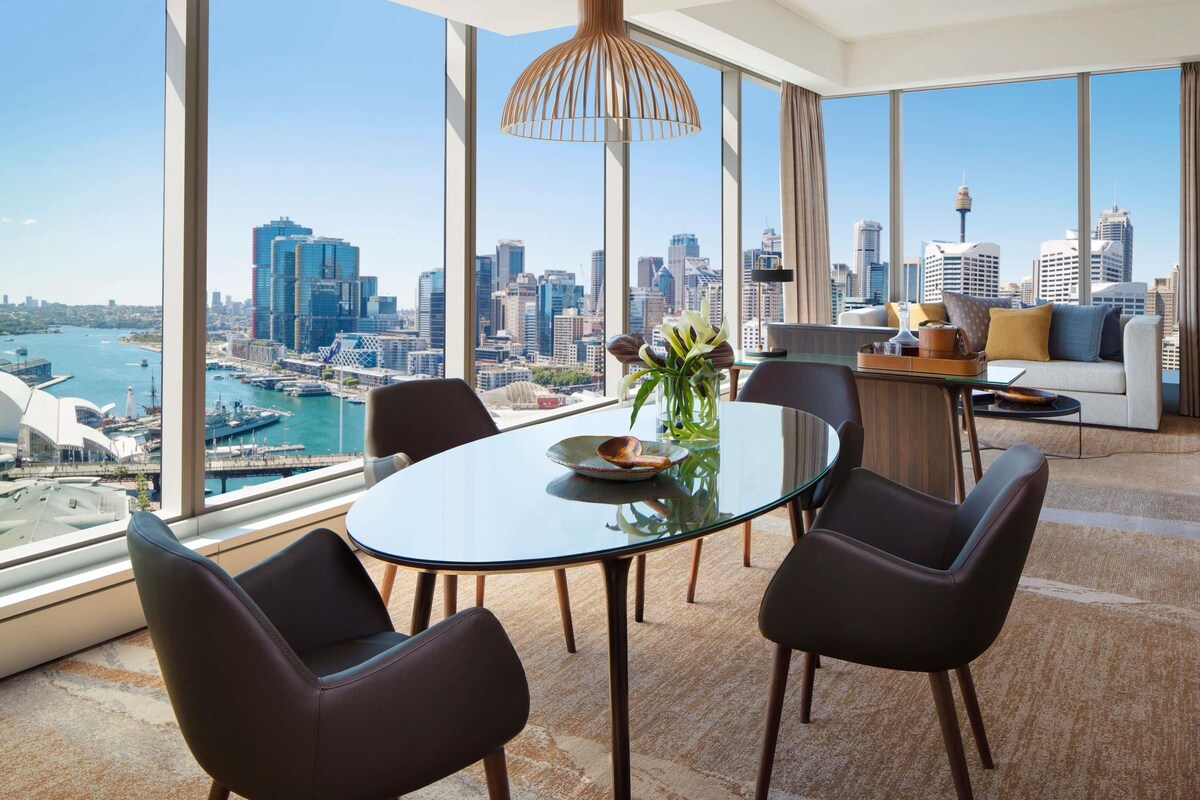 Un comedor moderno con vistas panorámicas de la ciudad, una mesa redonda de vidrio y sillas contemporáneas.