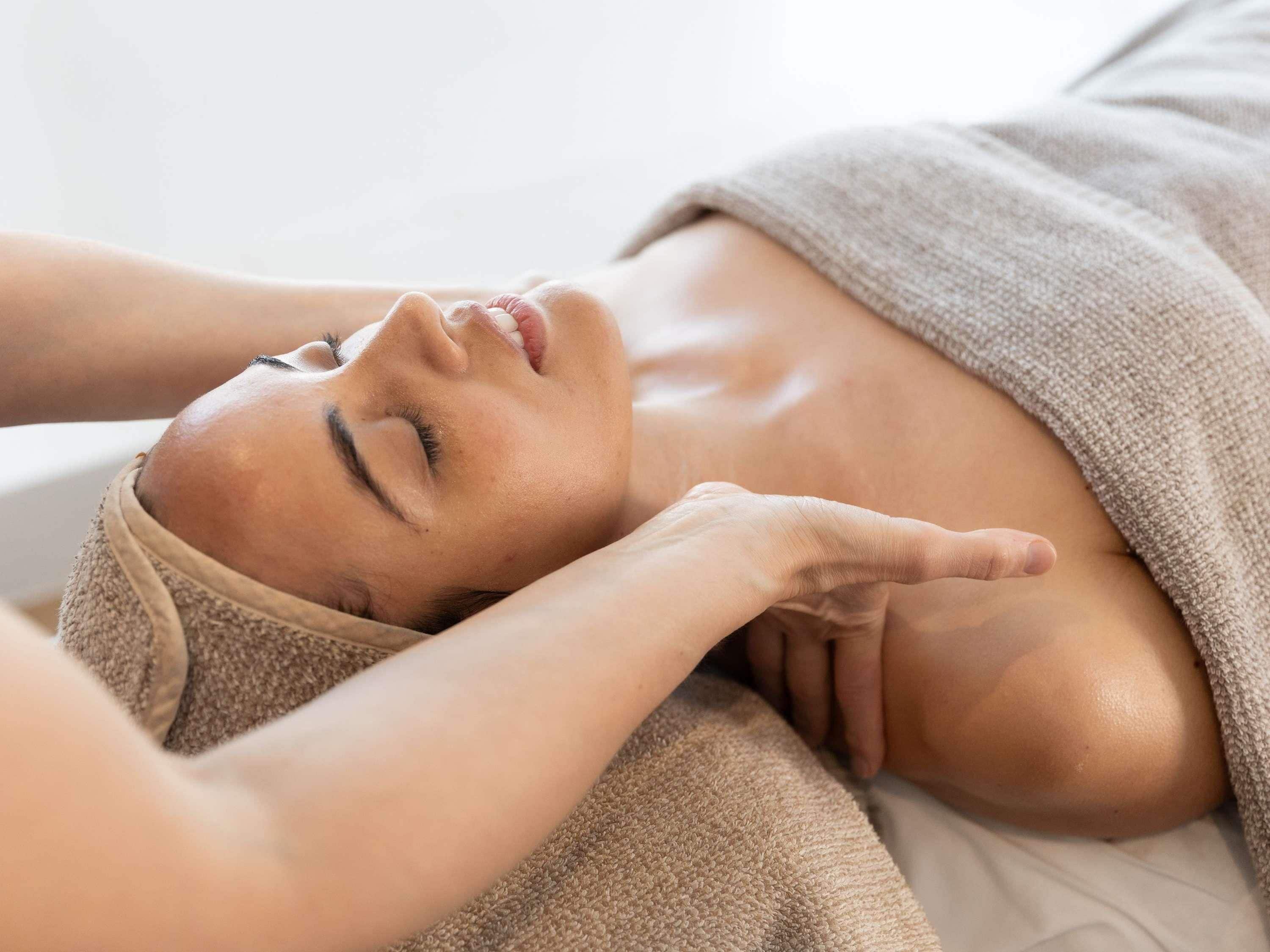 A person receiving a massage, with a towel covering their upper body.