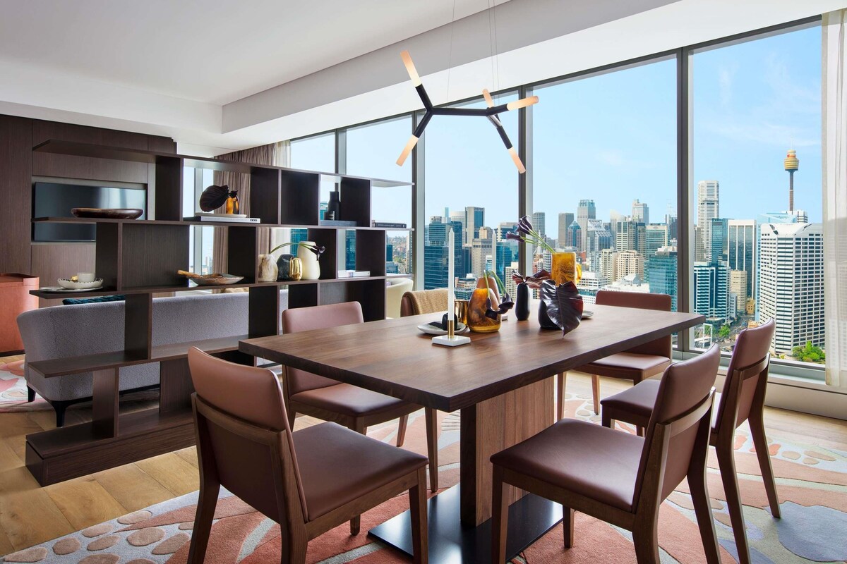 Un comedor moderno con vista a la ciudad, techo alto y diseño minimalista.
