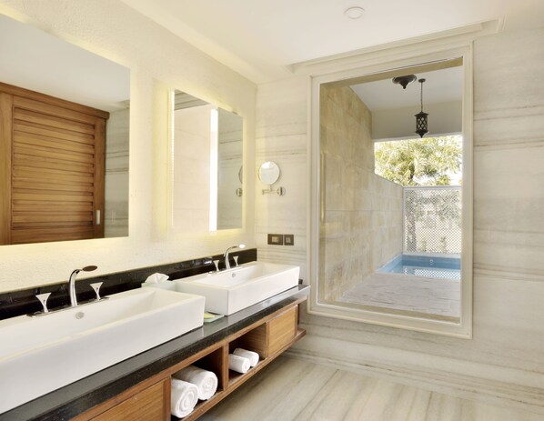 Un baño moderno con dos lavamanos, un espejo grande y vistas a una piscina exterior.
