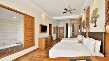 Habitación de hotel con una cama grande, televisión, cómoda de madera, baño con bañera y un panel decorativo en la pared.