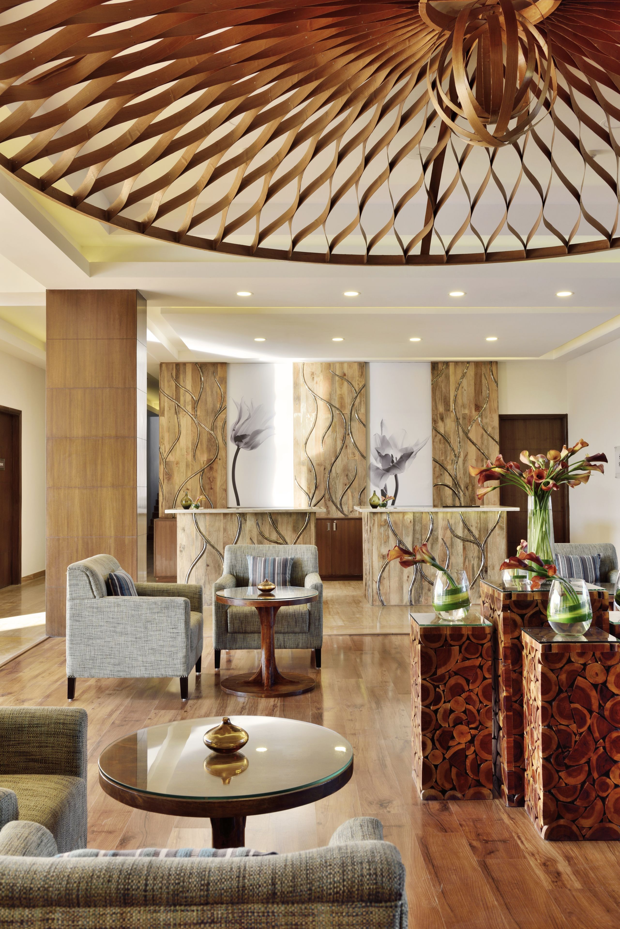 A modern lobby with a wooden ceiling, seating area, and a reception desk.