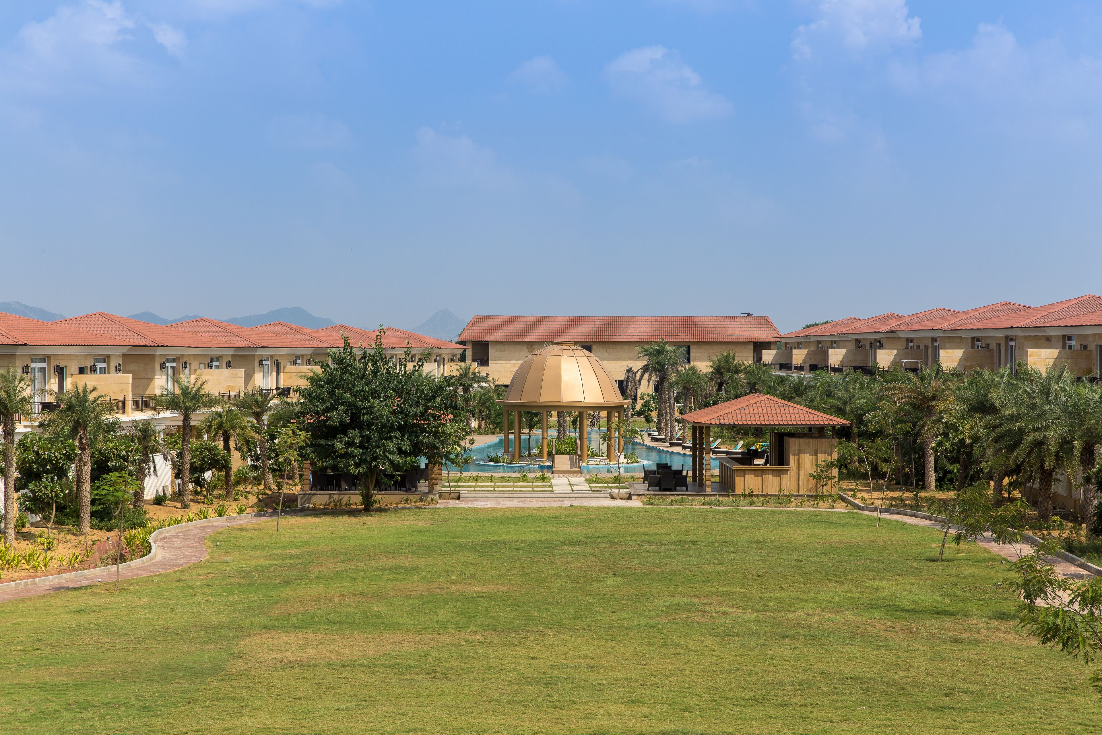 A hotel with multiple buildings, a central dome structure, and a well-maintained lawn.