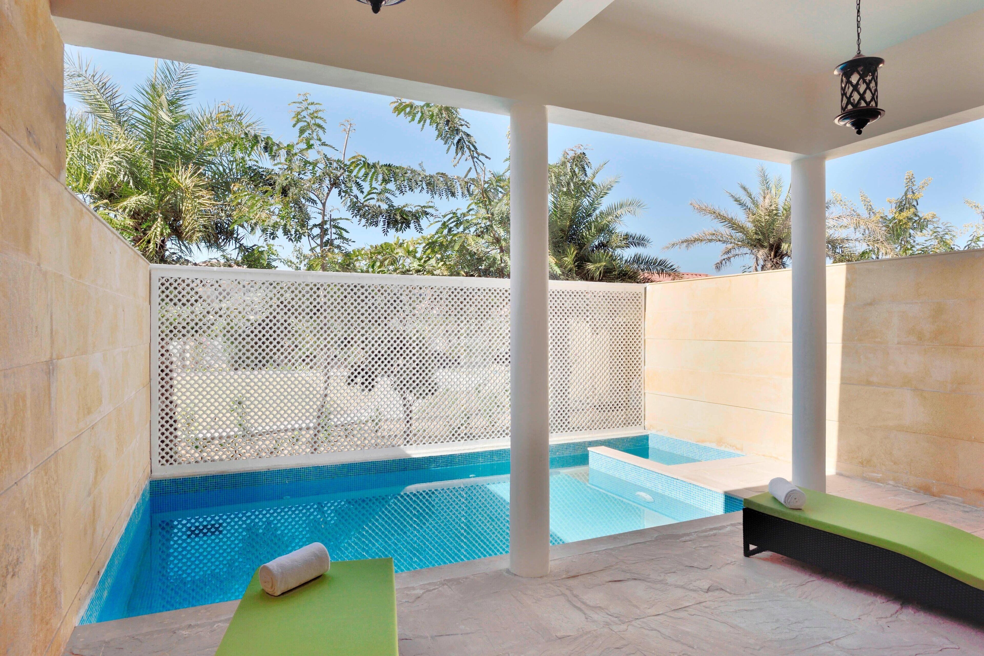 Un espace bien-être comprenant une petite piscine, une chaise longue et un banc.
