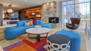 A modern living room with a sectional sofa, a round coffee table, and a stone fireplace. - Fairfield Inn & Suites Cuero (Cuero)