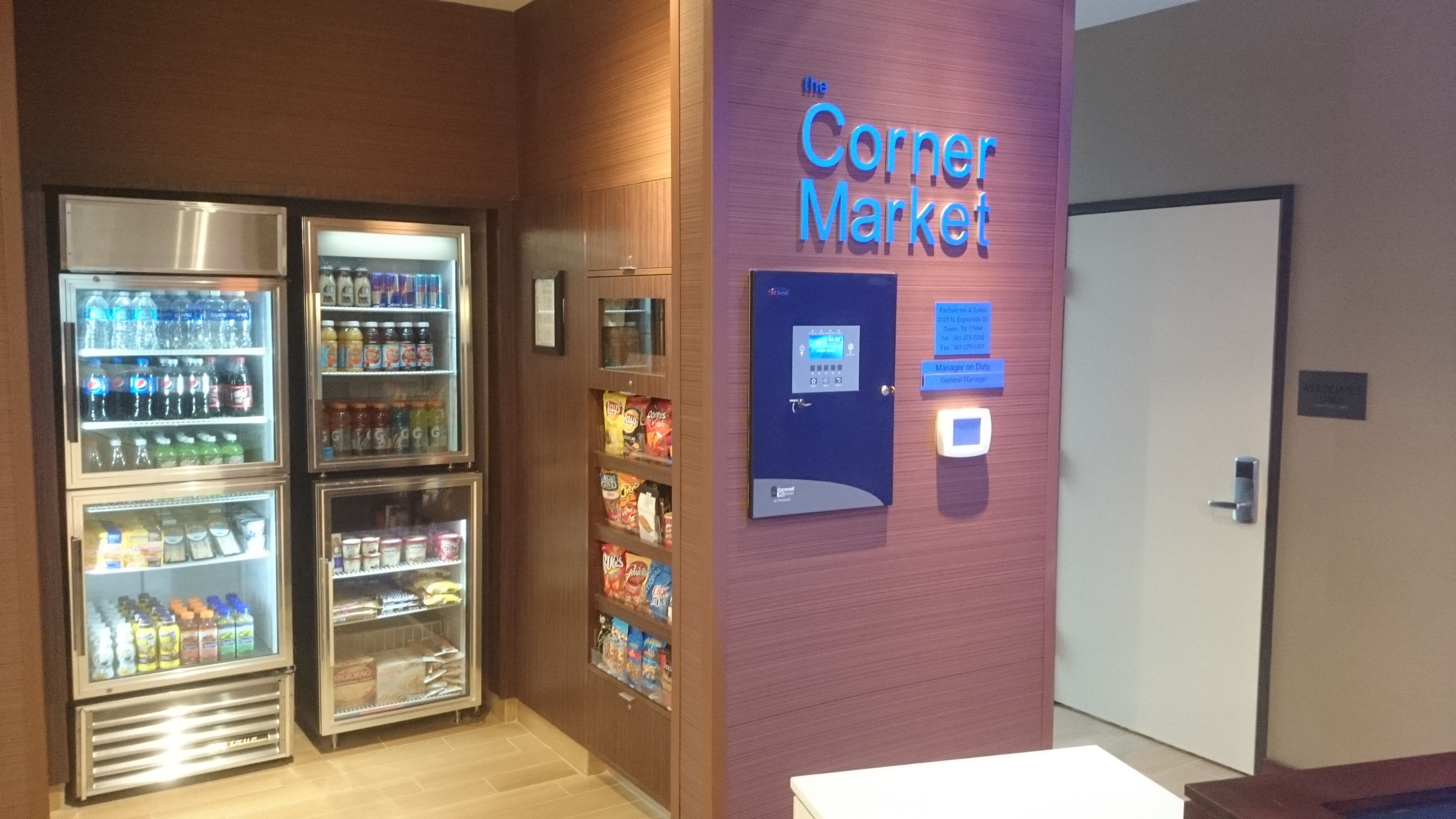 A corner market with refrigerated beverage dispensers and snack shelves.