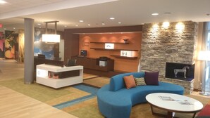 A modern lobby with a reception desk, seating area, and a stone fireplace. - Fairfield Inn & Suites Cuero (Cuero)