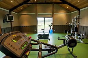 A gym with exercise equipment, a television, and a large window. - Poronui (Taharua)