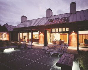 A house with a covered patio, outdoor seating, and a stone fireplace. - Poronui (Taharua)
