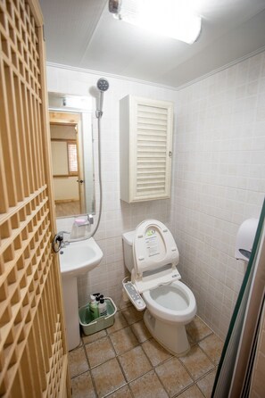 A bathroom with a toilet, a sink, a handheld showerhead, and a mirror. - Jiwoodang (Jeonju)