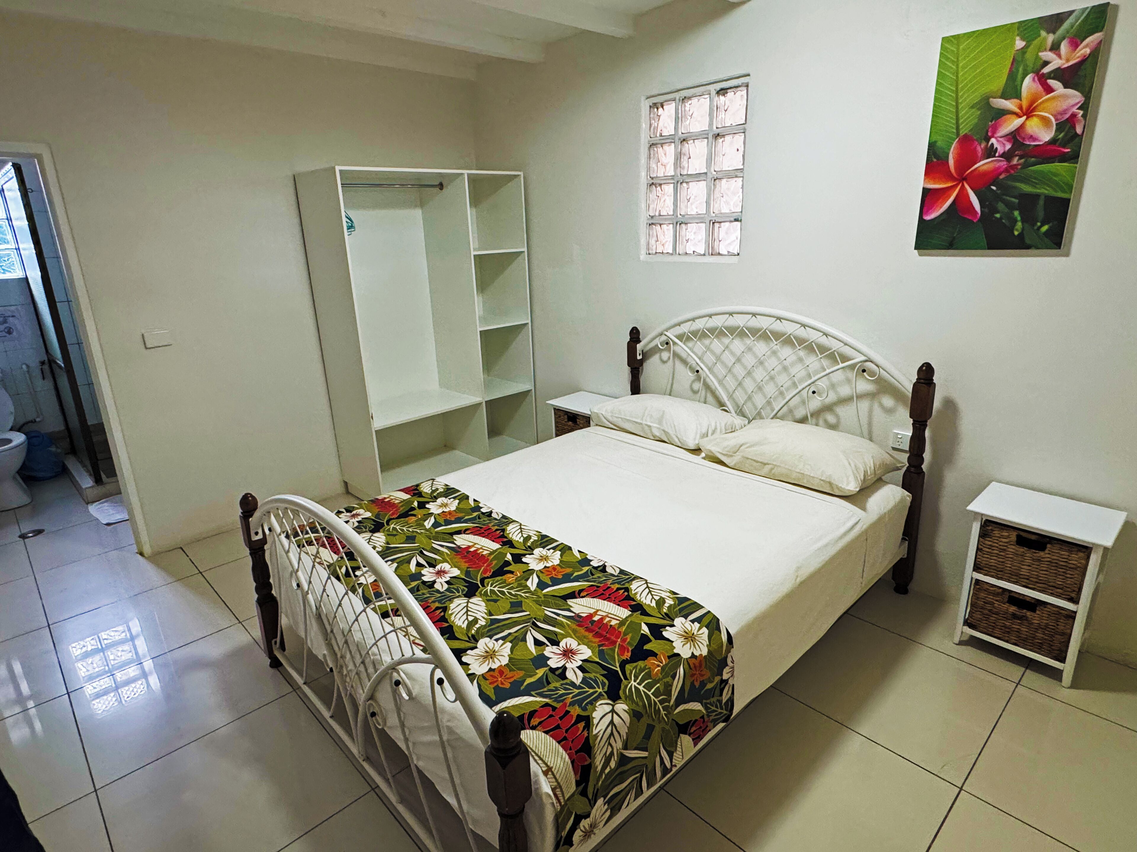 Quarto com cama, guarda-roupa, mesa de cabeceira e uma pequena mesa.
