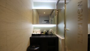 Une salle de bain moderne avec un miroir, un lavabo équipé de produits de toilette et une poubelle.