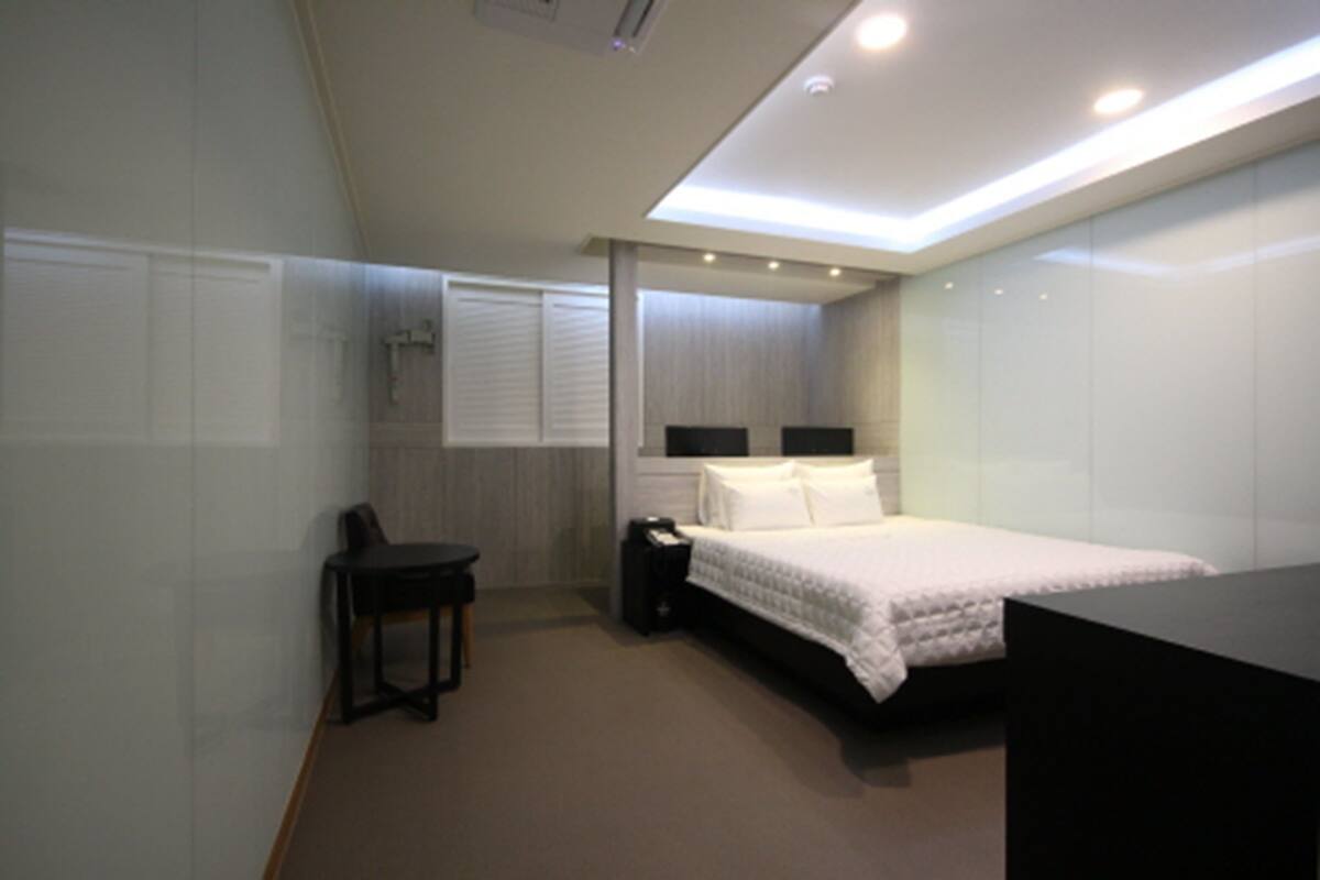 A modern bedroom with a bed, bedside tables, a desk, and a chair.