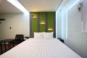Ein Hotelzimmer mit einem großen Bett, einem kleinen Tisch, einem Stuhl und einer grünen Wand mit integrierter Beleuchtung.